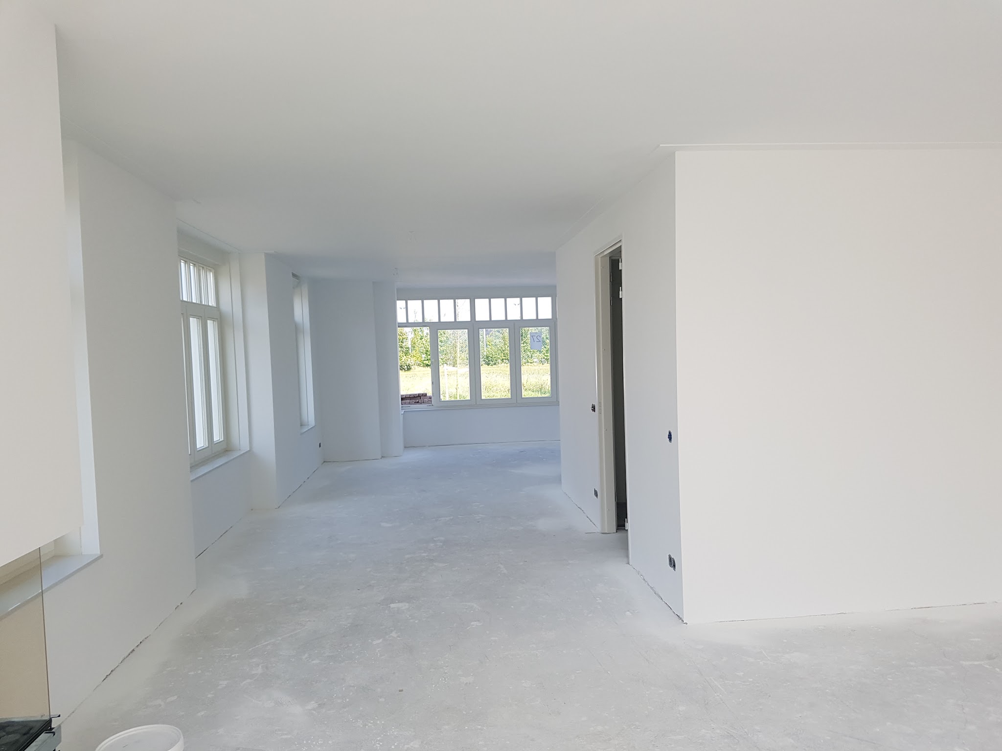 Doorlopende woonkamer met net gestucte witte muren en plafond